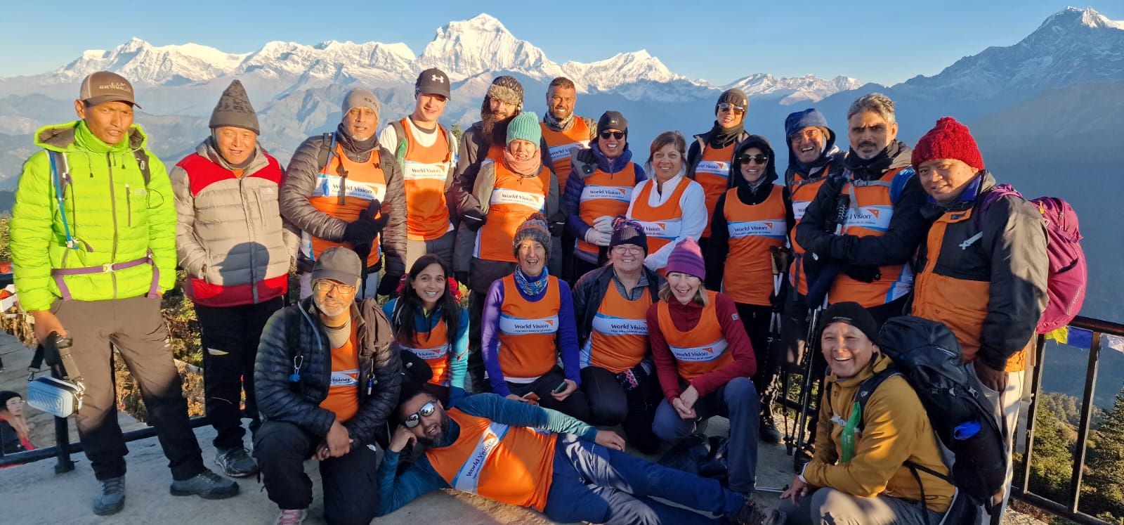 A group of World Vision supporters dressed in walking gear stand in front of a snow capped mountain range in Nepal