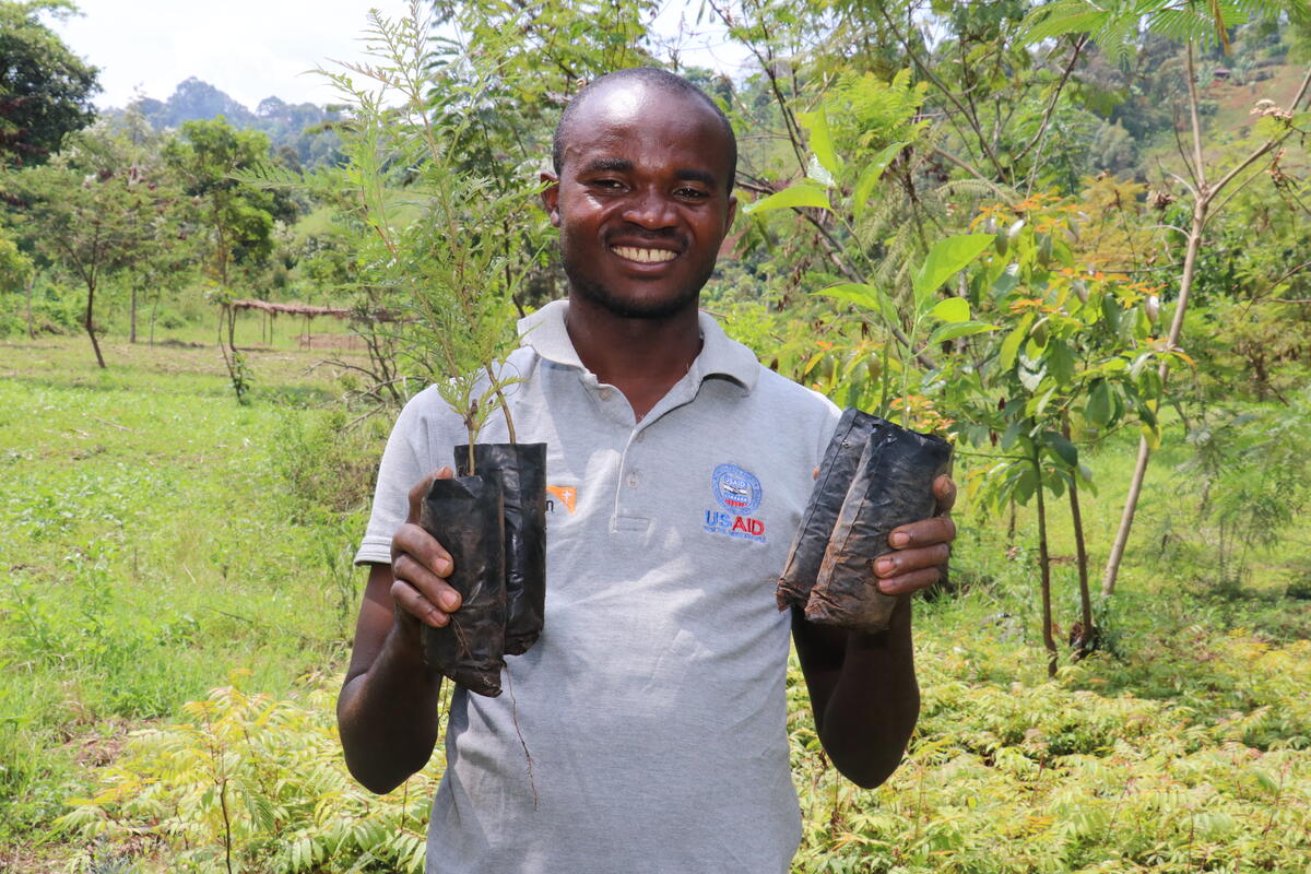 Man stands proudly holding the plants he is growing