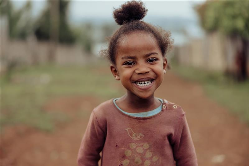 A young girl from Ethiopia smiles to the camera wearing a pink top