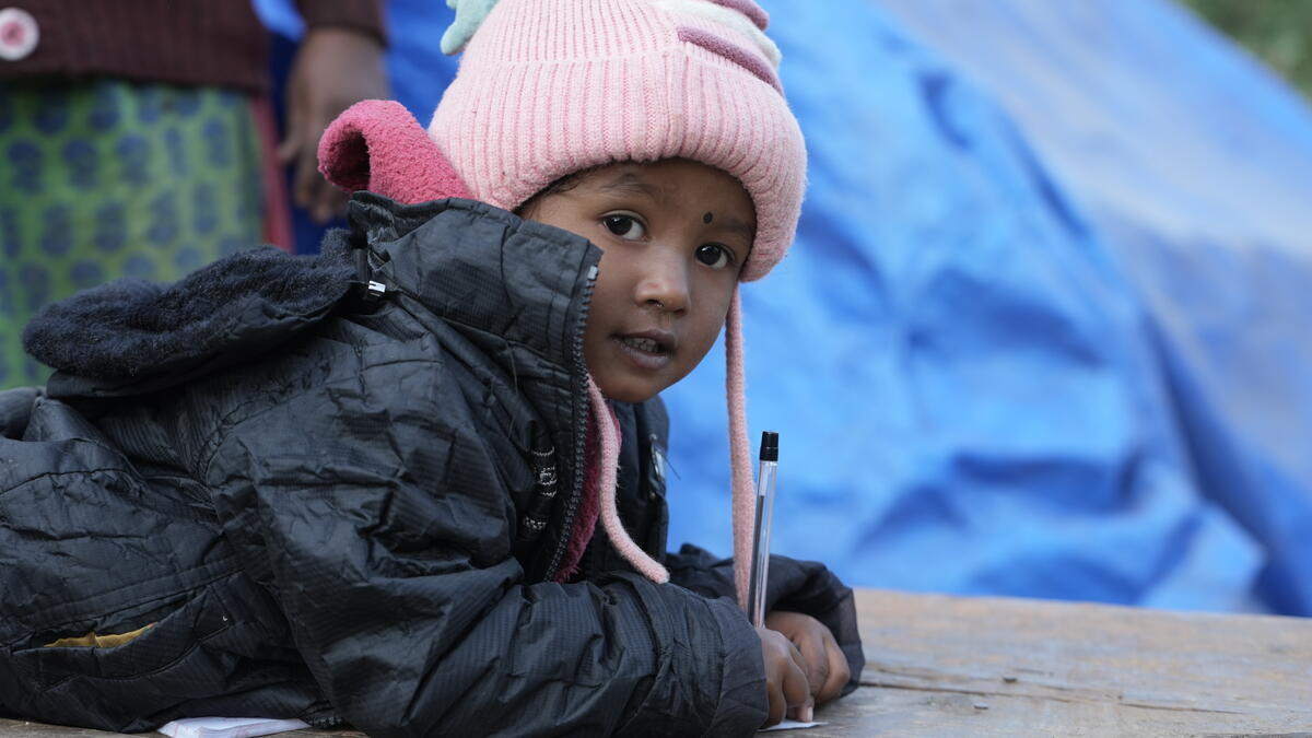 A child in Nepal wrapped up warmly in a winter coat and hat