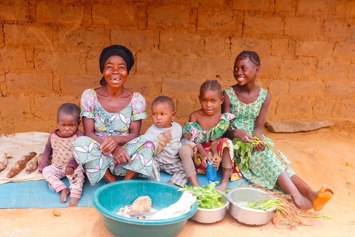 Mother and three children sit with buckets of food in the DRC