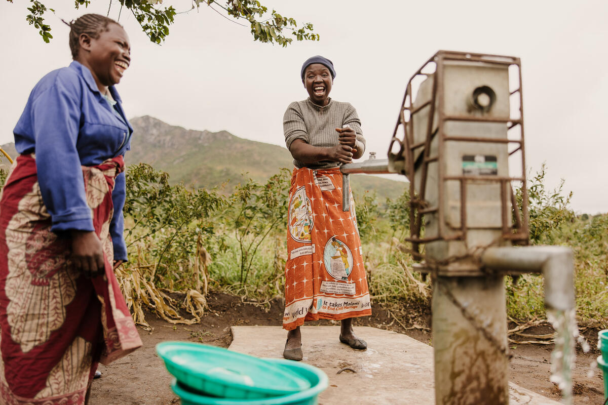 Woman standing smiling at a borehole in Malawi