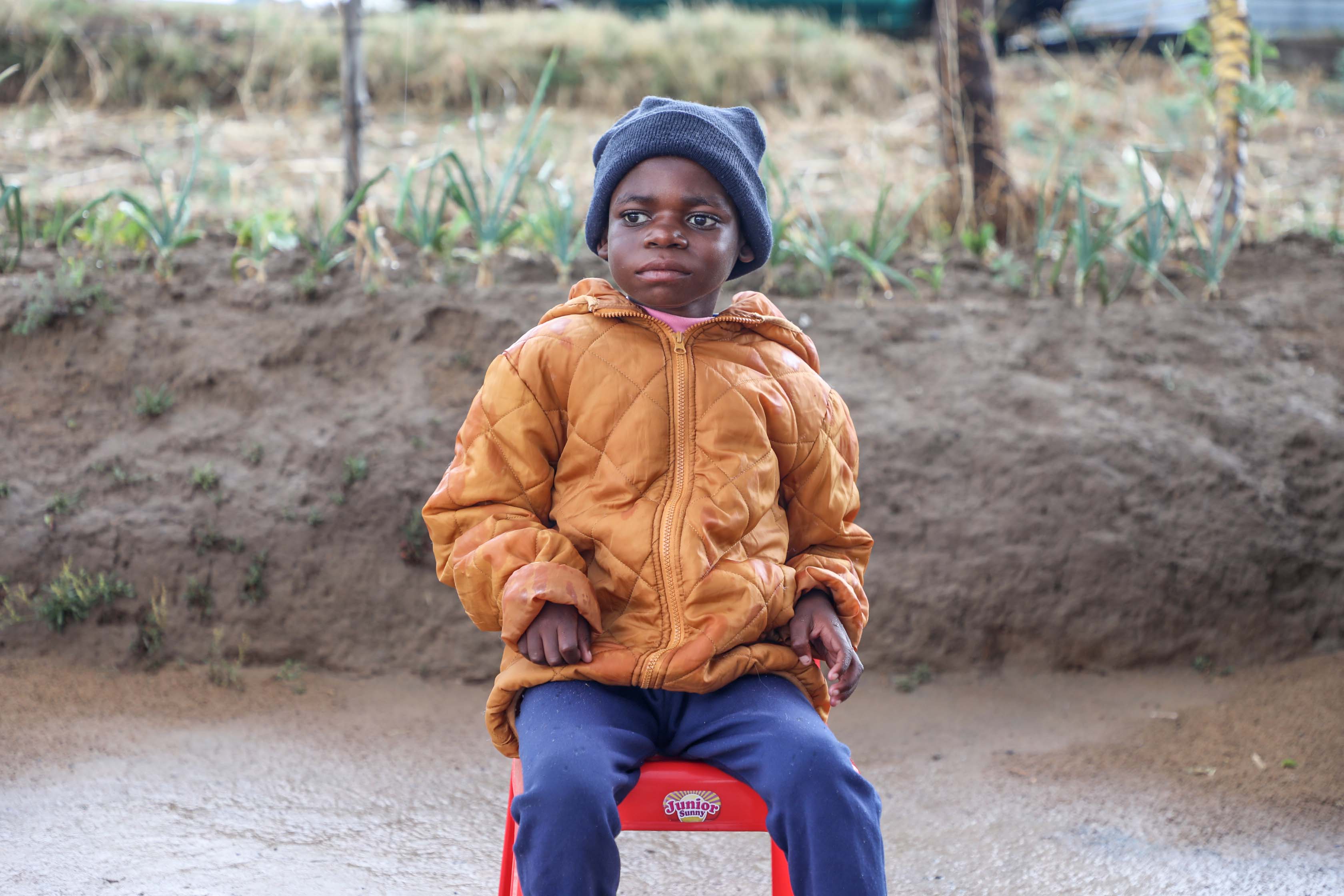 A young boy sat on a chair outside his house