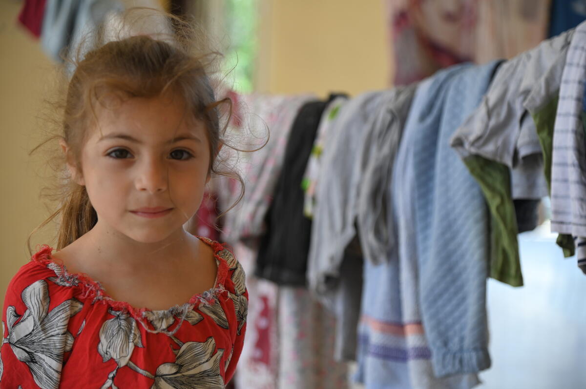 A young girl from Lebanon stands in front of a line of washing