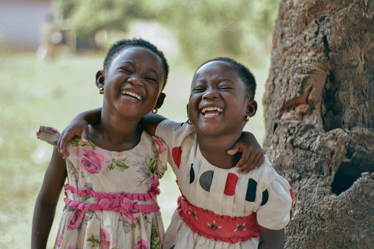 Two little girls pose for a picture with their arms around one another, Ghana