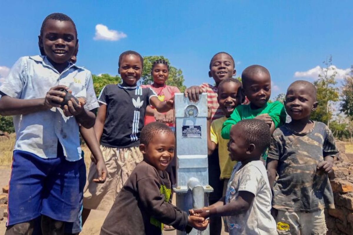 Children in Malawi, children smile and huddle around their new clean water tap