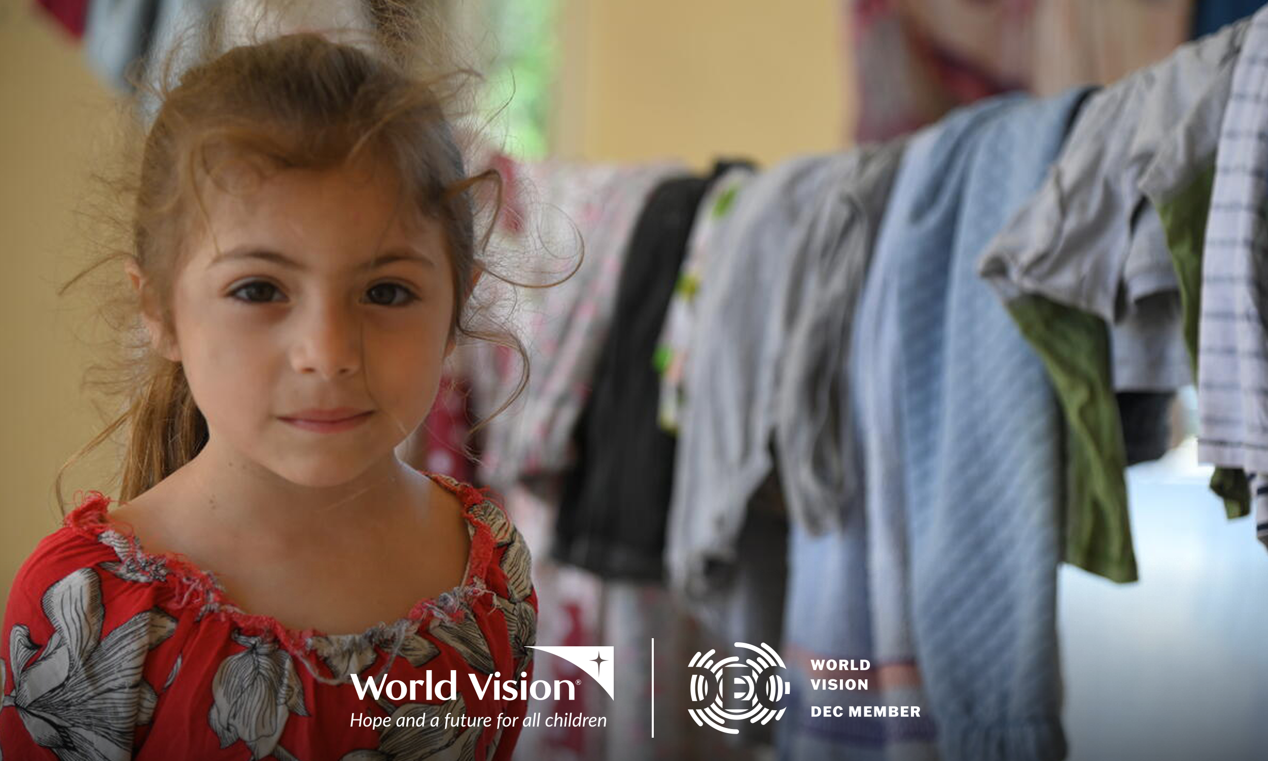 A young girl in Lebanon stands in front of an indoor washing line