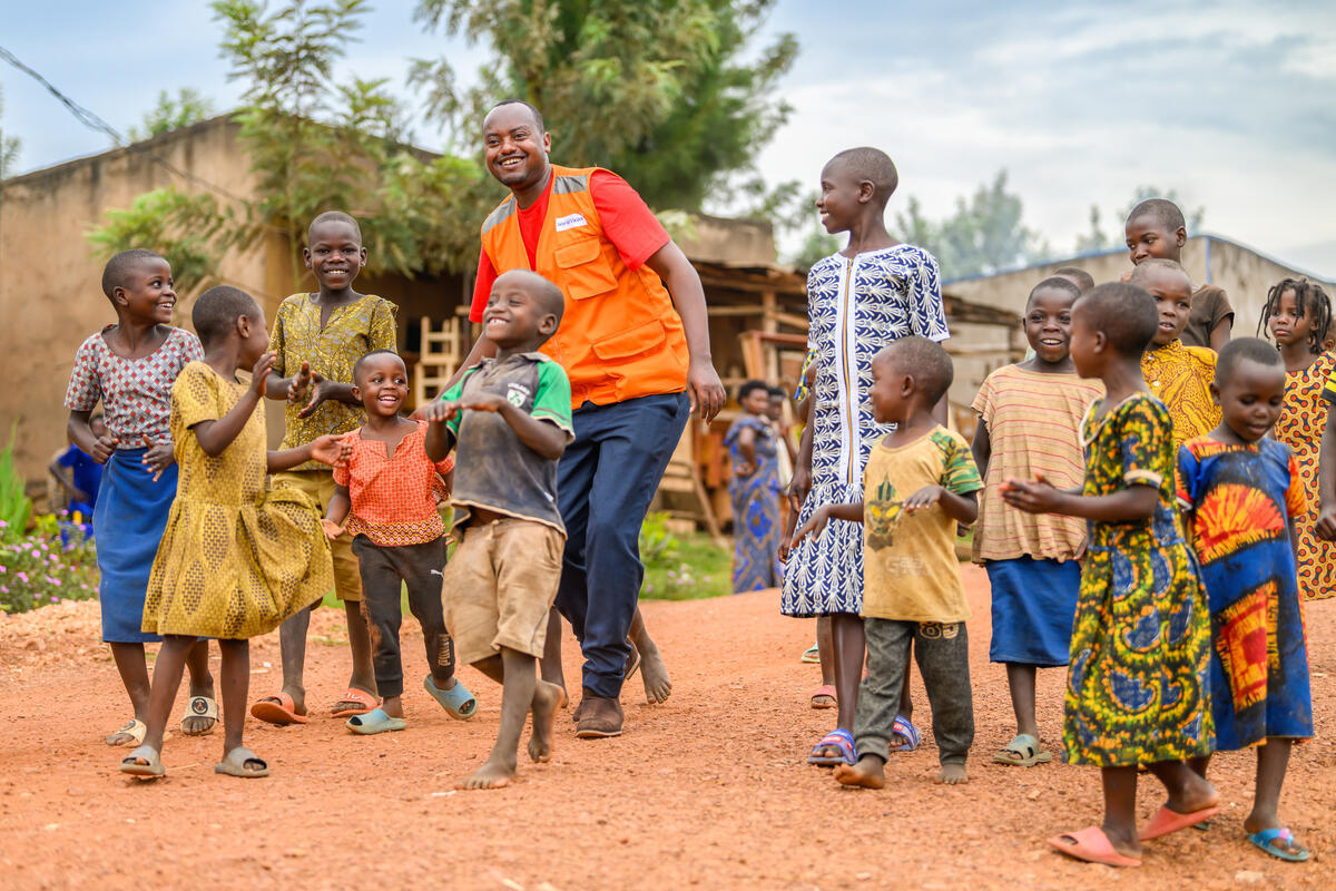 World Vision Rwanda staff member walking with children