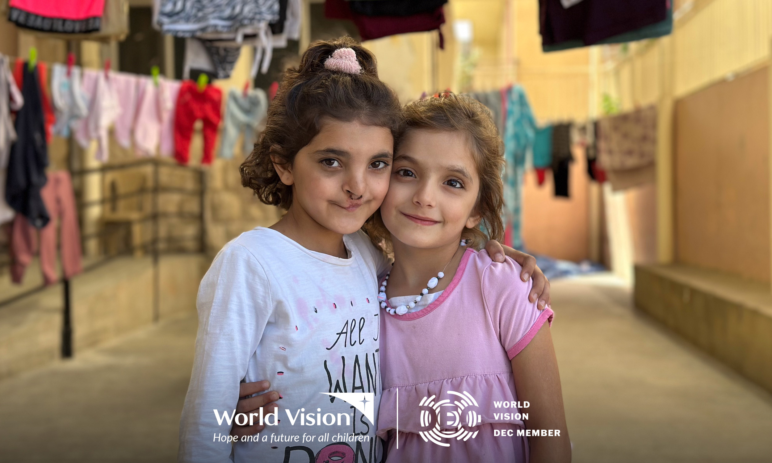 Two young girls standing together in a residential courtyard.