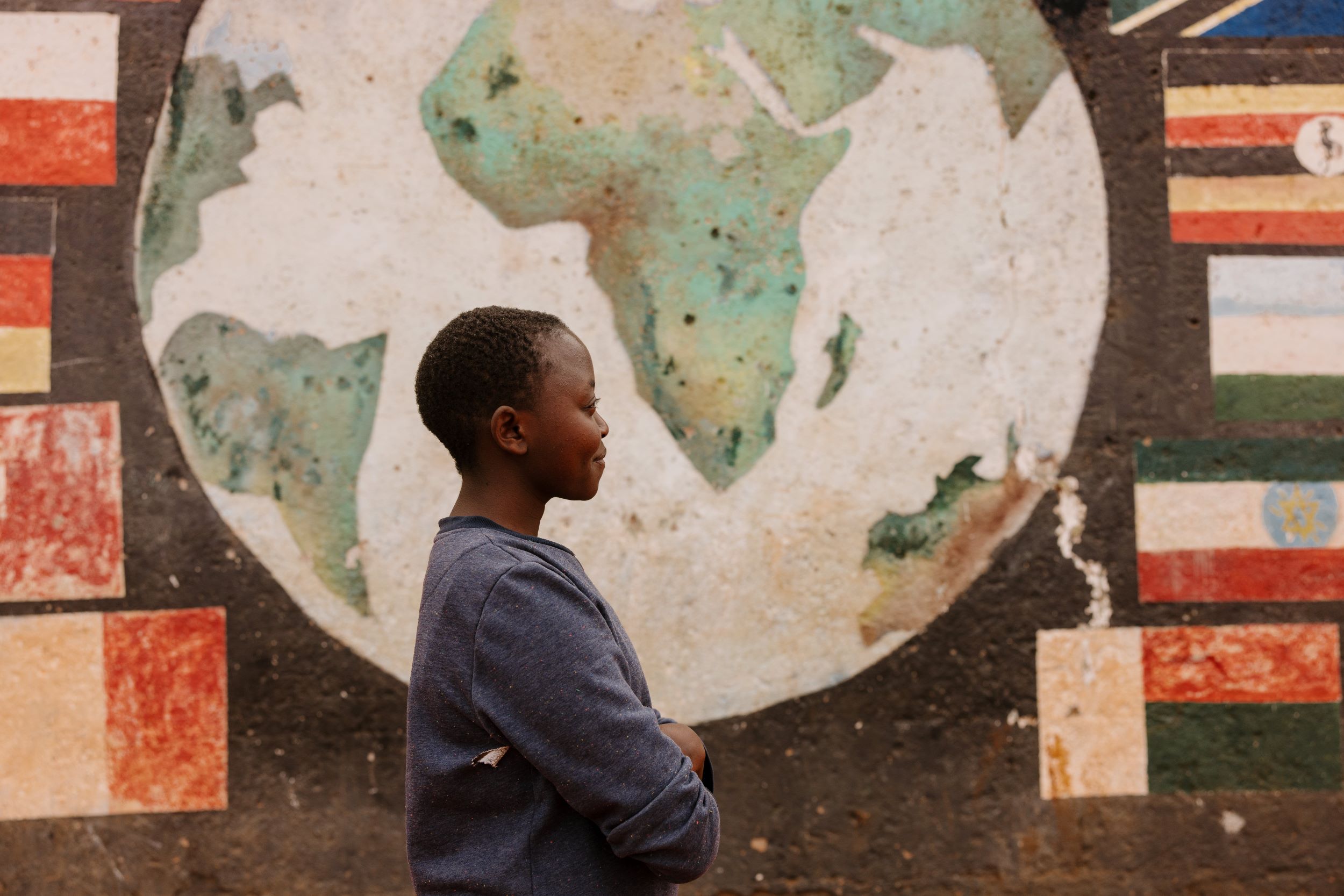 Side view of smiling Kenyan girl in front of world map