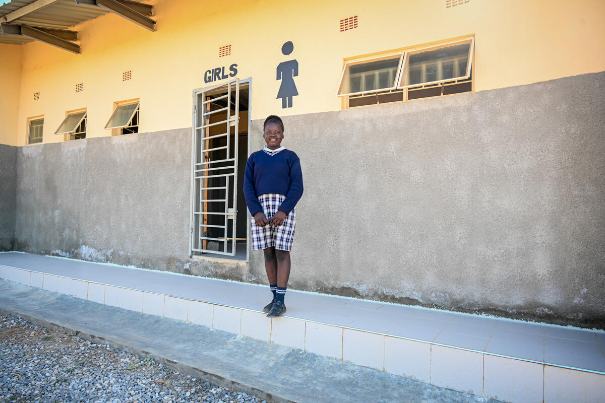 A girl standing outside of a newly build toilet facility, Zambia