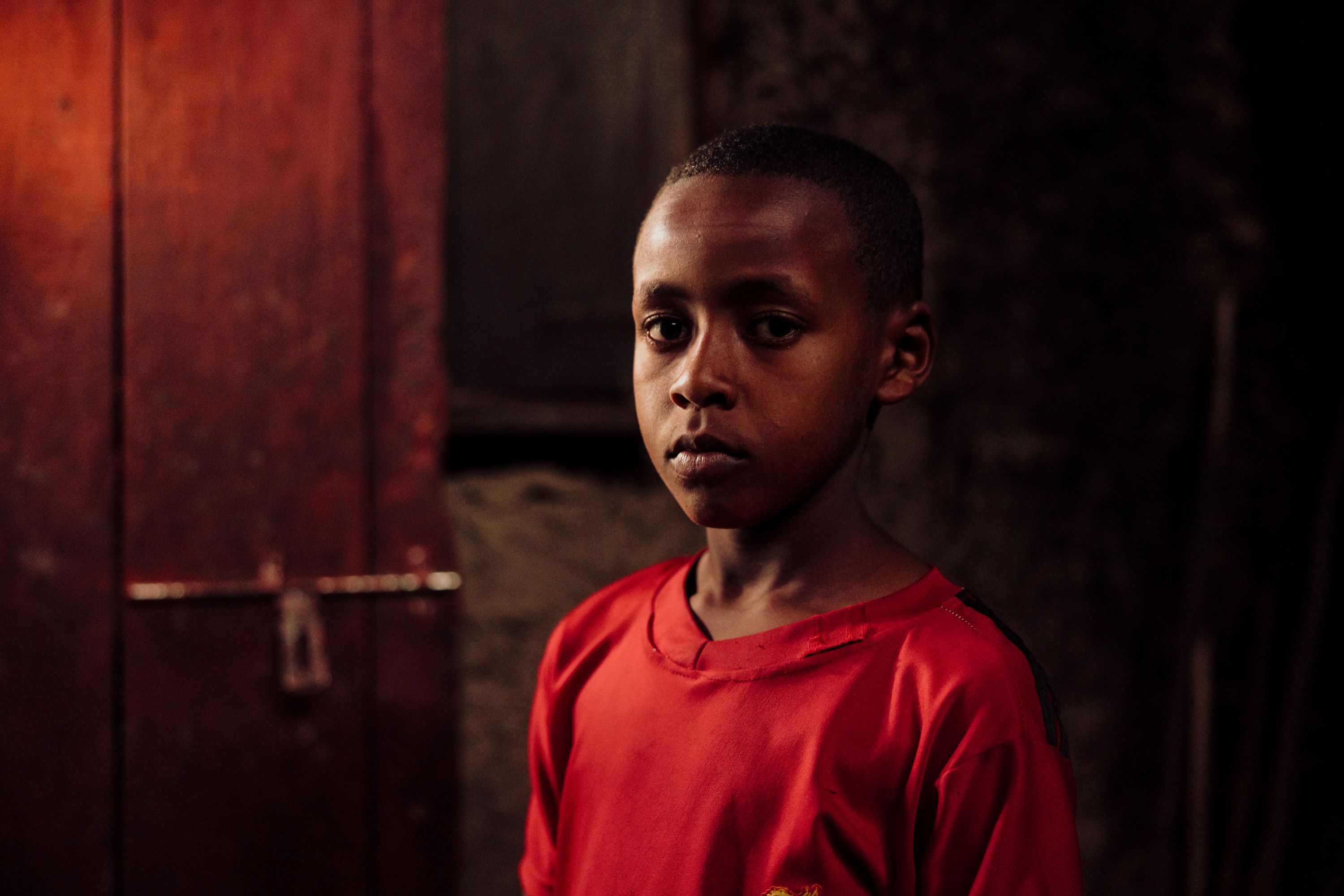 Mensur, pictured wearing a red t-shirt, is back at school thanks to child sponsors