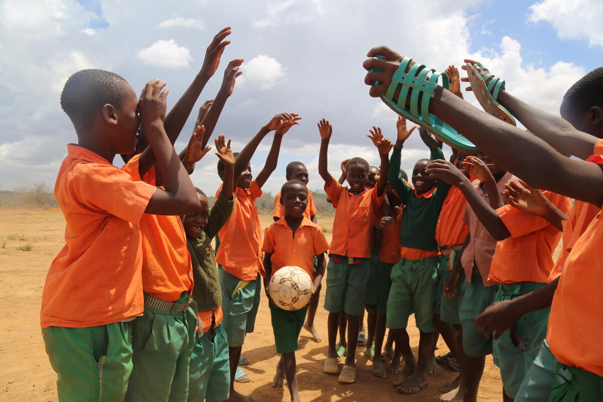 A group of boys play with a football outside, Kenya