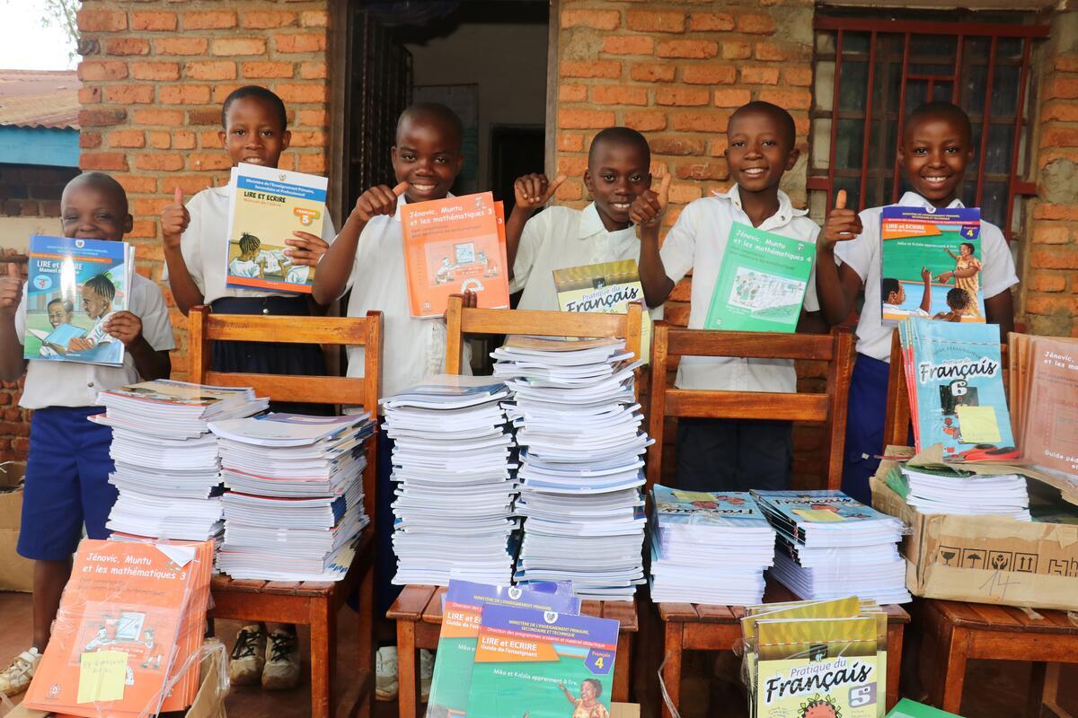 Children standing in front of large piles of books