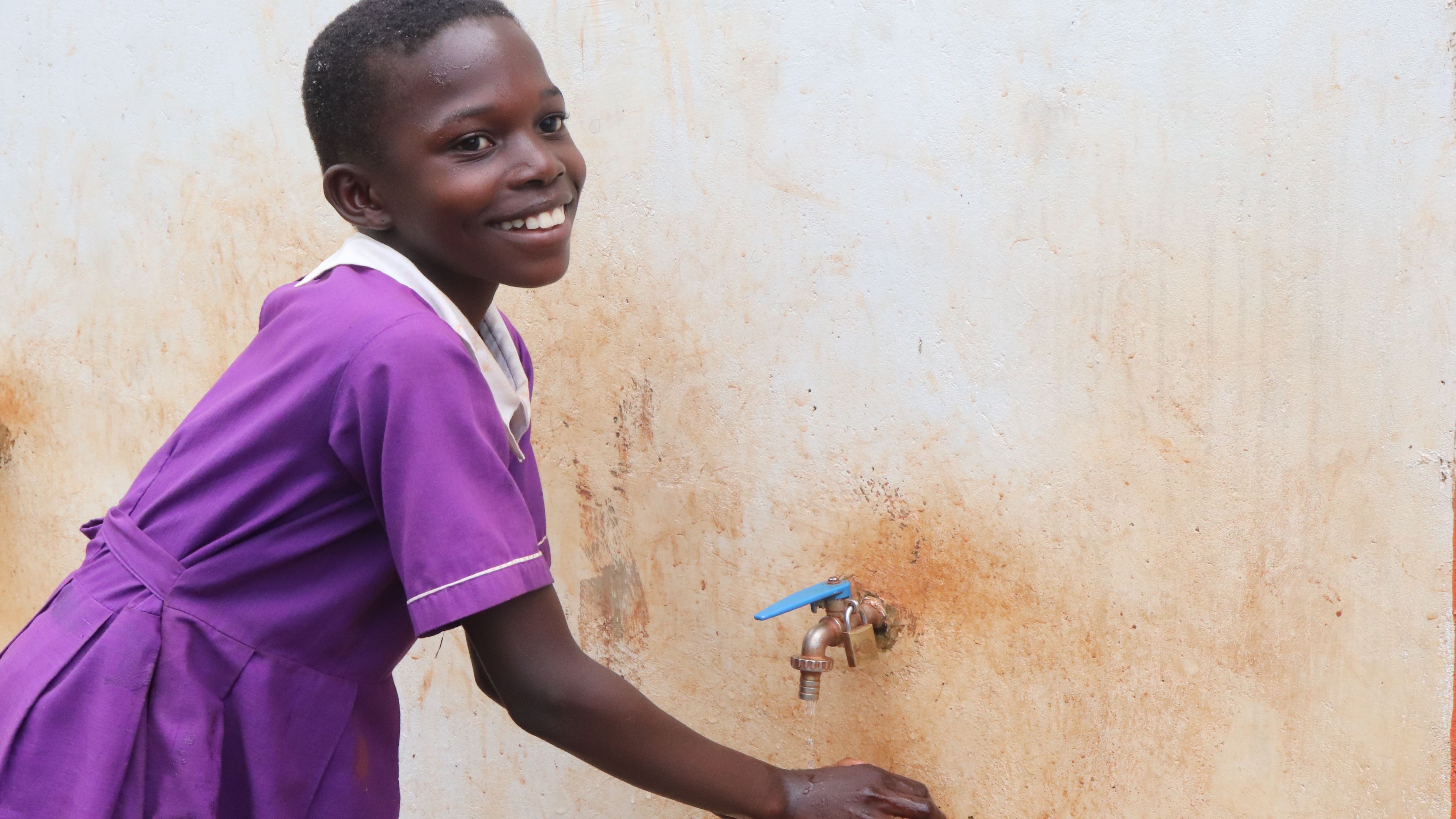 Jovia, girl age 10 washing her hands outside new toilet blocks built at her primary school in Uganda