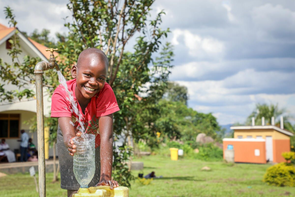 Ugandan girl smiles as she collects clean water from a health clinic