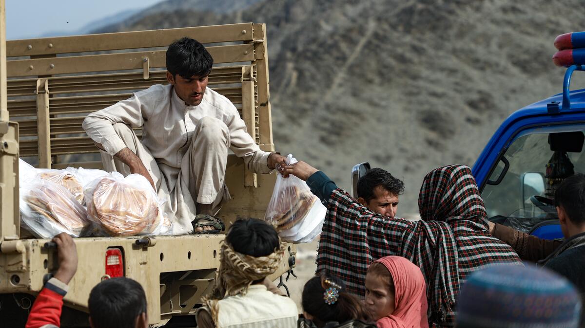 Truck with Afghan people handing out food assistance parcels