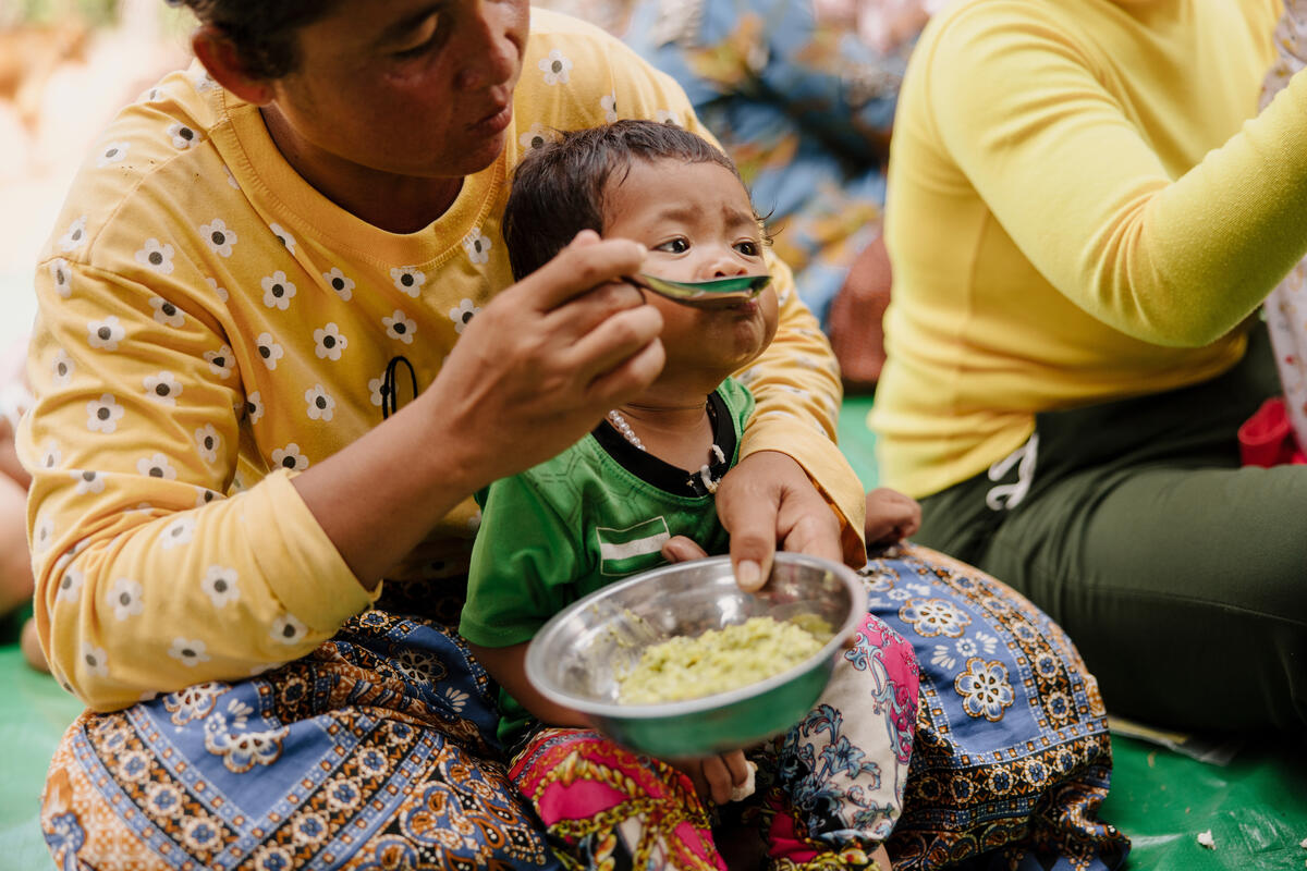 A mother feeding her young child food, Cambodia